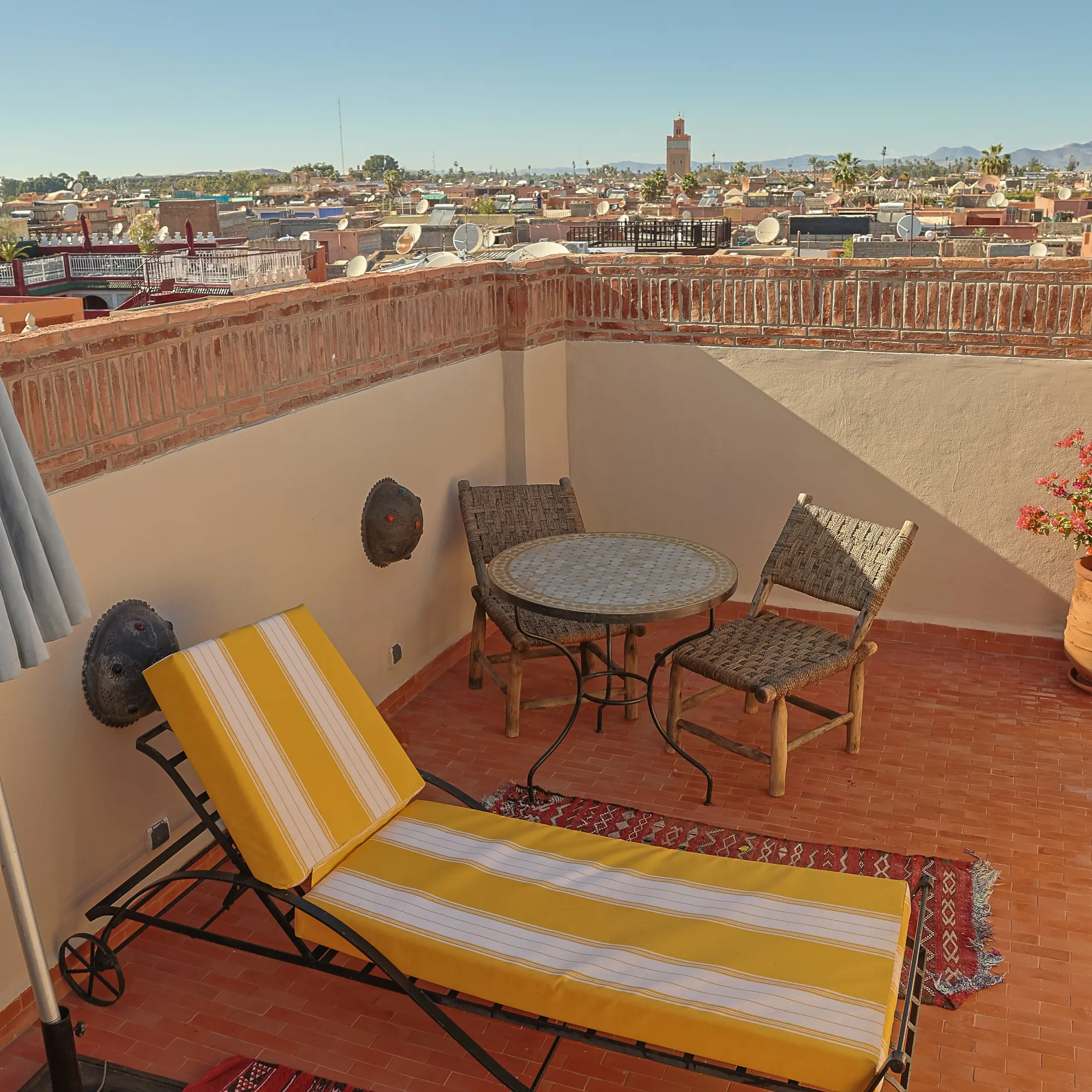 The rooftop terrace of the Horizon Room with a lounger, table and views over Marrakech