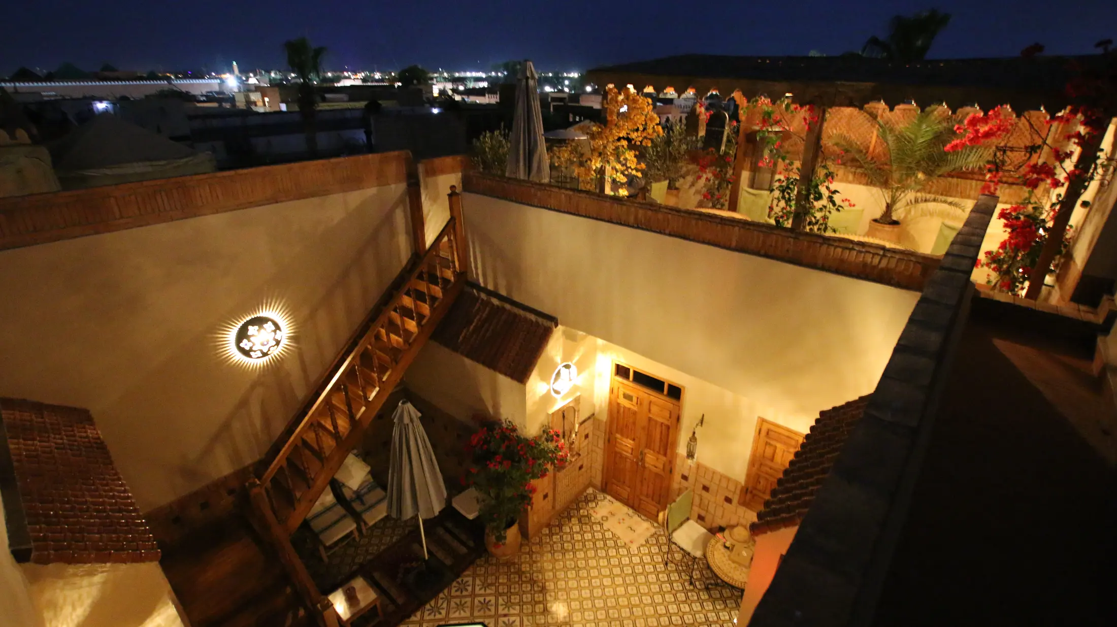 Night over Marrakech: the city lights beyond the riad's lit courtyard and terraces