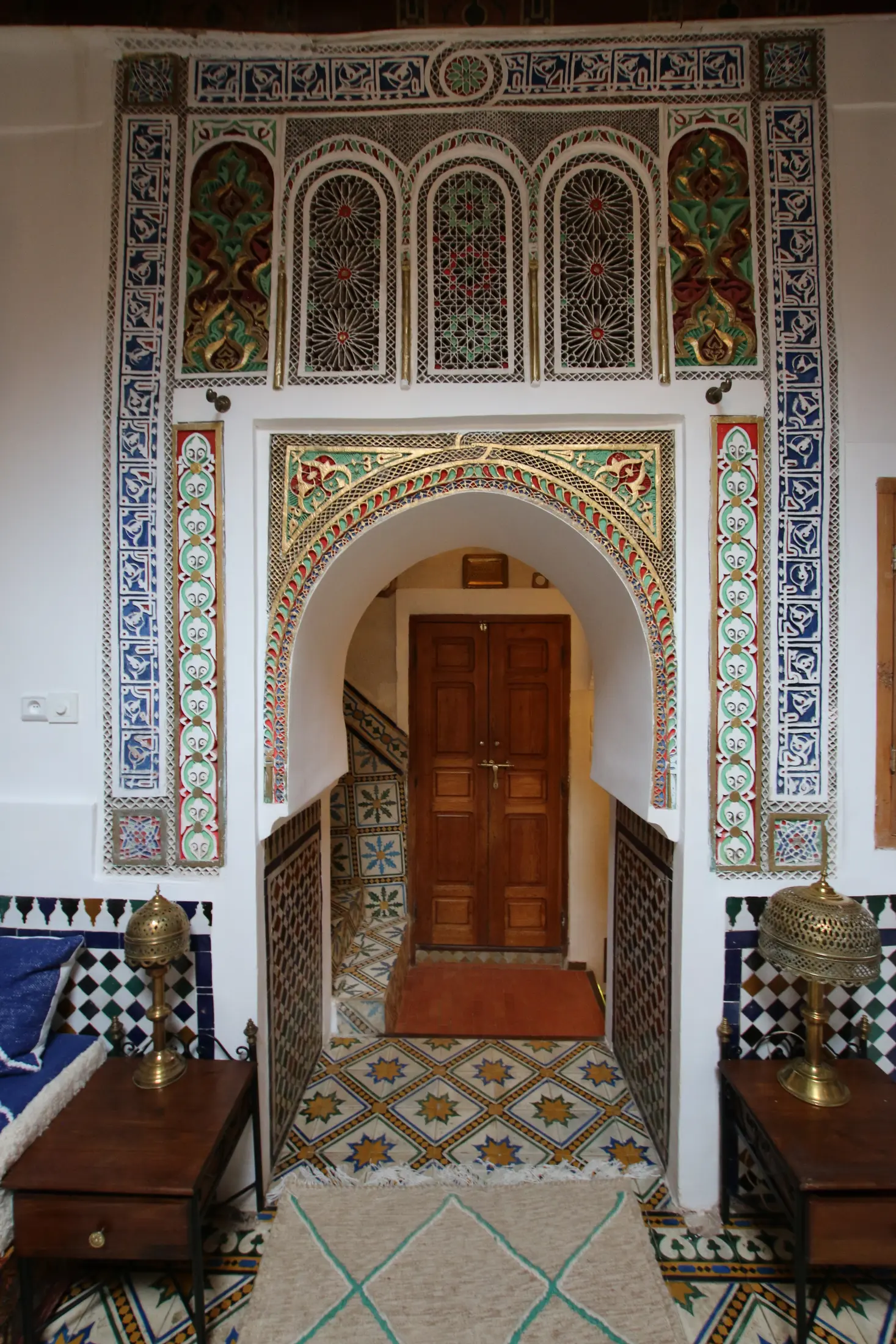 Carved plaster arch and painted cedar doors at the salon entrance