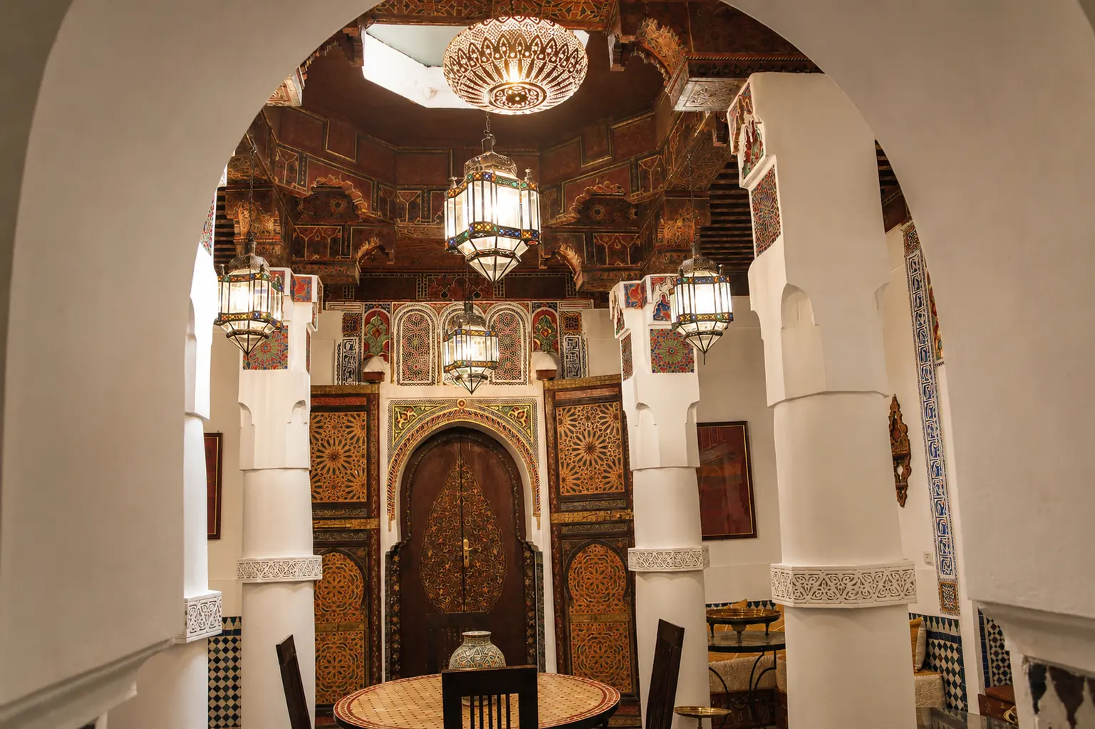 The Grand Salon framed by its great carved arch, lanterns hanging beneath the painted ceiling